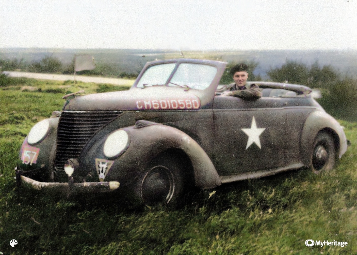 Le Capitaine Duncan avec sa nouvellement capturée (et repeinte) voiture d’état-major quelque part dans la brèche de Falaise en août 1944. La voiture, une Matford (Ford) française de 1933, fut plus tard surnommée « the passion wagon ».